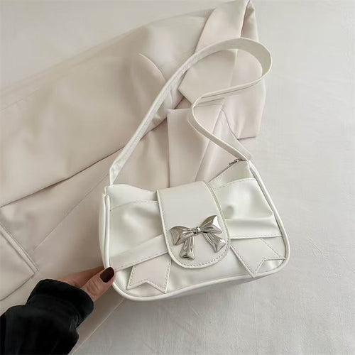 White handbag with a bow detail held against a light background